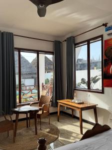 a living room with a table and chairs and windows at Jamaica House in Nungwi