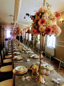 a long table with plates and flowers on it at Pensjonat Nowy Młyn in Kostrzyn nad Odrą
