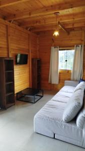 a living room with a white bed and a tv at Chalé Azaléia in Campo Alegre