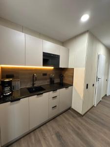 a kitchen with white cabinets and a sink and a refrigerator at CUBE Alpine Stay in Bürs