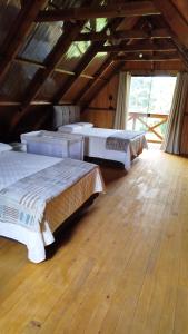 three beds in a room with a wooden floor at Chalé Azaléia in Campo Alegre