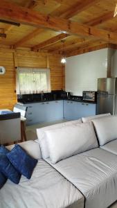 a living room with a white couch in a kitchen at Chalé Azaléia in Campo Alegre