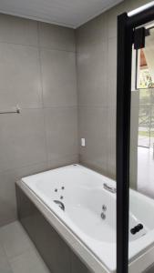 a white bath tub in a bathroom with a window at Chalé Azaléia in Campo Alegre +8 photos