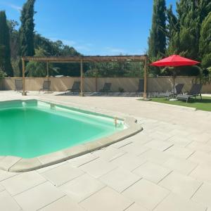 a swimming pool with an umbrella and a patio at Camping le Faucon d'or in Montricoux