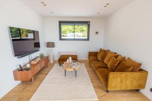 a living room with a couch and a tv at Superbe Maison 4ch proche de la mer avec piscine in Bénerville-sur-Mer