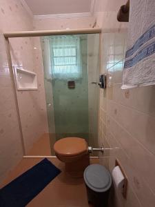 a bathroom with a toilet and a glass shower at Fascinação Café Hotel in Cunha