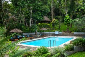 a swimming pool in a resort with tables and chairs at Spice Village Thekkady - A CGH Earth Experience in Thekkady