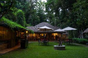 a patio with tables and umbrellas in a yard at Spice Village Thekkady - A CGH Earth Experience in Thekkady