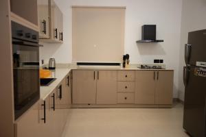 a kitchen with white cabinets and a black refrigerator at Zanziluxe Residences in Zanzibar City