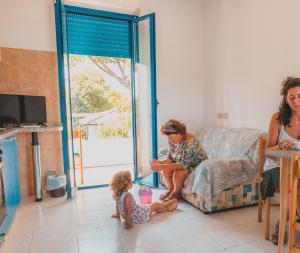a woman and a child sitting on a couch in a living room at Residence Il Sole in Porto Corsini