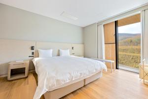 a white bedroom with a large bed and a large window at Villa Mori - Odin Hills in Kutchan