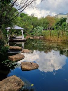 a pond with rocks and a gazebo in a garden at The 506 Hotel in Midrand
