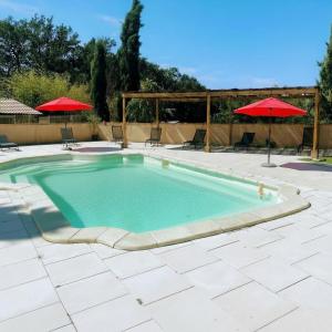 a large swimming pool with two red umbrellas at Camping le Faucon d'or in Montricoux