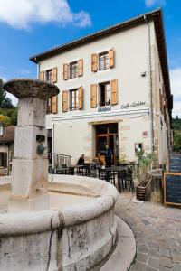 a building with a fountain in front of it at Hôtel Bistrot Les Tanins in Saint-Antoine