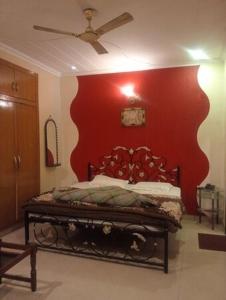 a bedroom with a bed with a red wall at Hotel Anmol in Dehradun