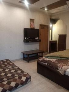 a room with two beds and a flat screen tv at Hotel Anmol in Dehradun