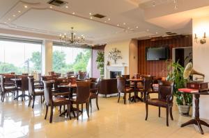 a dining room with tables and chairs and a tv at Hotel Athina in Kato Loutraki