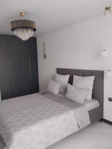 a bedroom with a bed with white sheets and a chandelier at Balka-centr Tiraspol in Tiraspol
