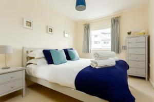 a bedroom with a large bed with blue and white pillows at Coxswain's Cabin - Moments from Hamworthy Beach and Park in Poole