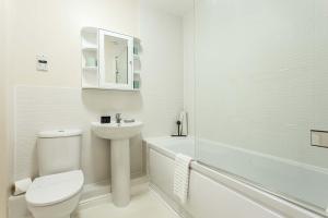 a white bathroom with a toilet and a sink at Coxswain's Cabin - Moments from Hamworthy Beach and Park in Poole