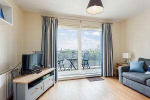 a living room with a tv and a couch and a balcony at Coxswain's Cabin - Moments from Hamworthy Beach and Park in Poole