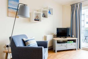 a living room with a blue chair and a television at Coxswain's Cabin - Moments from Hamworthy Beach and Park in Poole +25 photos