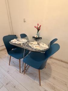 a glass table with blue chairs and a vase with flowers at Downtown Apartman near City Center & Miskolc Plaza in Miskolc
