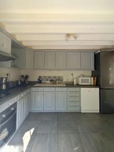 a kitchen with white cabinets and a black refrigerator at Gîte rural de Criquemanville - Maison familial 4 chambre avec grand jardin in Sassetot-le-Mauconduit +20 photos