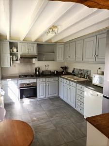 a large white kitchen with white cabinets and appliances at Gîte rural de Criquemanville - Maison familial 4 chambre avec grand jardin in Sassetot-le-Mauconduit