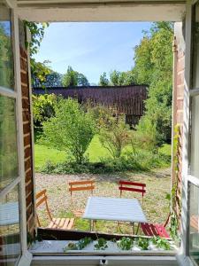 a view of a table and two benches through a window at Gîte rural de Criquemanville - Maison familial 4 chambre avec grand jardin in Sassetot-le-Mauconduit