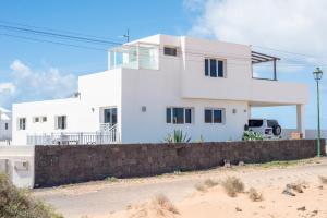 a white house with a fence in front of it at Lanzarotearena in Tinajo