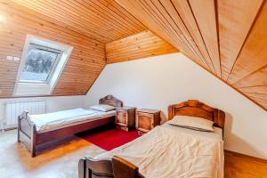 two beds in a room with a wooden ceiling at Apartments Mija in Krotica