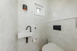 a white bathroom with a sink and a toilet at Lua Beach House in Zandvoort