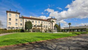 a large white building with a green lawn in front at Savoia Hotel Regency in Bologna
