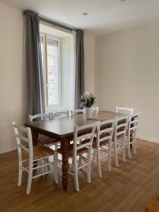 a dining room table with white chairs and a wooden table at Maison de ville in Lannion