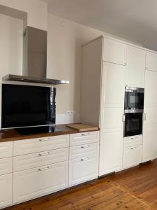 a white kitchen with white cabinets and a microwave at Maison de ville in Lannion
