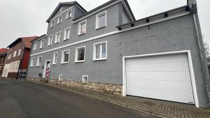 a gray building with two garage doors on a street at Ferienwohnung zur Apotheke in Hessen