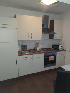 a kitchen with white cabinets and a stove top oven at Ferienwohnung zur Apotheke in Hessen