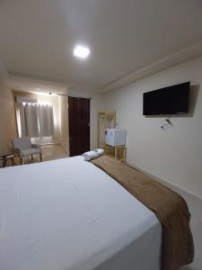 a bedroom with a large white bed and a flat screen tv at Pousada Serra do Torreão in João Câmara