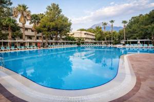 a large pool at a resort with chairs and trees at Rai Foresta Tekirova & SPA in Kemer