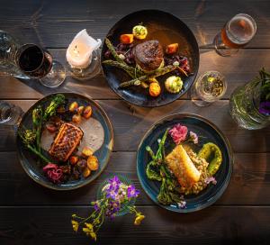 a wooden table with three plates of food on it at Miðhraun - Lava resort & Restaurant in Midhraun