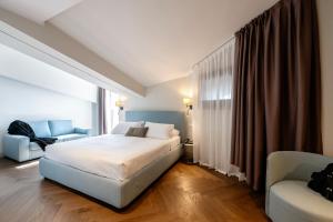 a bedroom with a bed and a chair and a couch at Hotel Carlton in Treviso