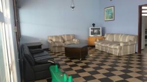 a living room with a couch and chairs and a tv at casa azul in Itanhaém