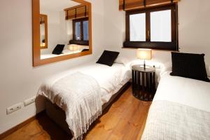 1 dormitorio con 2 camas y espejo en Pleta de Nheu 2 by FeelFree Rentals, en Baqueira Beret