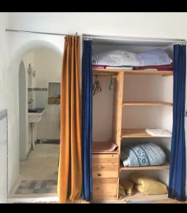 a room with a bunk bed with blue curtains at RIAD Adam in Sidi Ifni