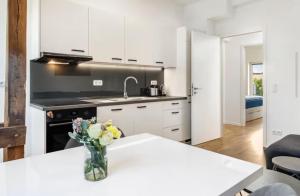 a kitchen with white cabinets and a vase of flowers on a table at Elb Park Suite in Wittenberge