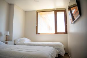 two beds in a room with a window at Apart Sei - Rada Tilly - in Rada Tilly