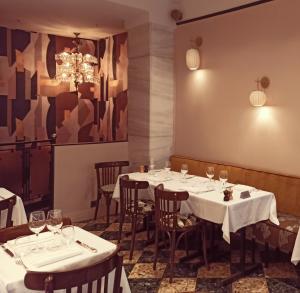 a restaurant with white tables and chairs and a chandelier at Hôtel George Washington in Paris
