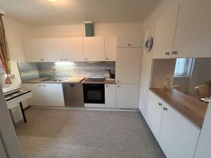 a small kitchen with white cabinets and a sink at Küstenhuus in Utersum