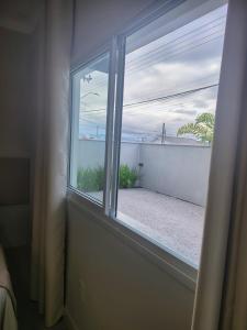 a window in a bedroom with a view of the ocean at Studio 02# Aconchego e tranquilidade em Floripa Muito Top e tranquilo in Florianópolis